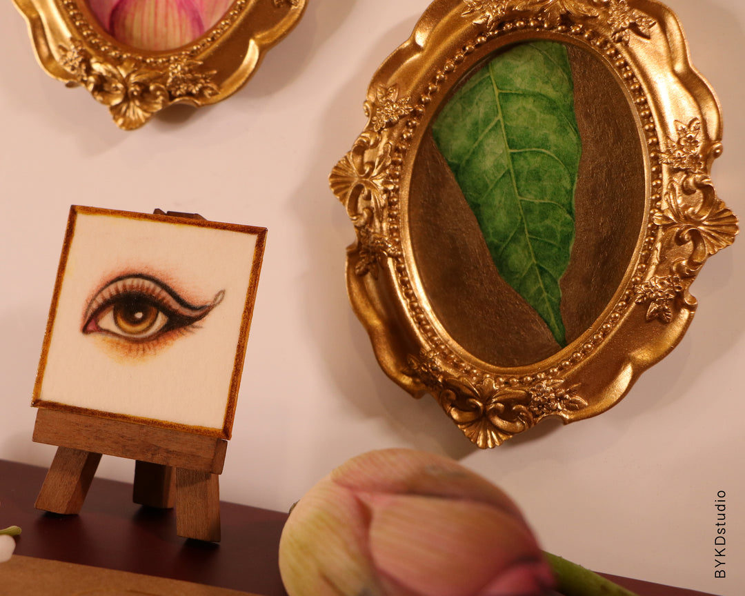 Decorative setup with gold-framed mirrors and a small easel with an eye illustration.