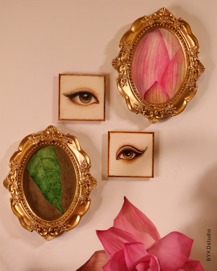 Decorative wall art with gold frames containing eyes and leaves on a beige background.